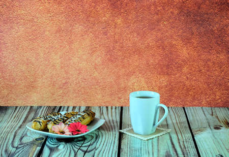 A white ceramic mug with tea and a plate with three eclairs and a red flower stand on a wooden...