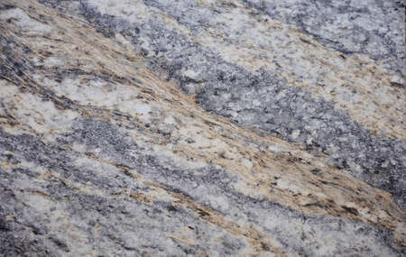 Dark gray granite with streaks and blots of brown and white. Background, texture.