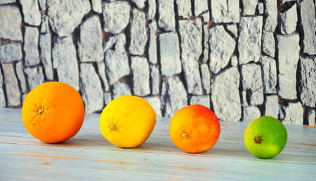 Whole fruits of orange, lemon, grapefruit and lime lie in a row on a wooden table. Close-up.