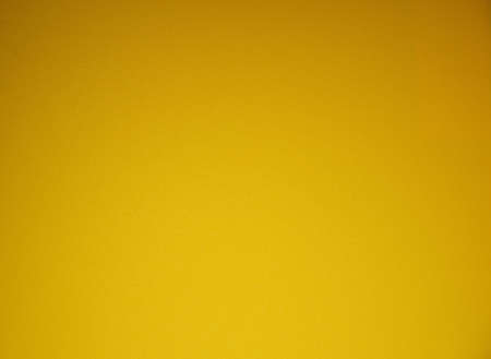 Bright yellow monochrome background with vignetting, rough surface close-up. Texture.の写真素材