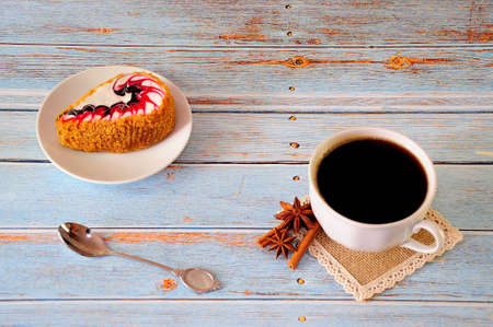 A cup of black coffee and a dragon biscuit cake on a white ceramic plate. Close-up.の写真素材