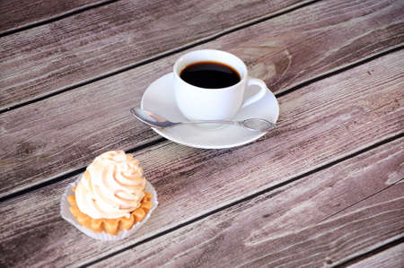 Shortcake cake basket with cream and a cup of black coffee on a saucer. Close-up.の写真素材