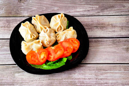 Plate with freshly cooked manti, lettuce and chopped tomato. Close-up.の写真素材