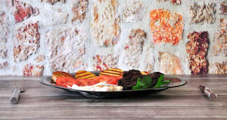 Lightly burnt beef steak with fried potatoes, tomato, garlic and fresh parsley. Close-up.の写真素材