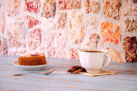 Sponge cake on a plate and a cup of black coffee on a plate with a spoon decorated with anise and cinnamon sticks. Close-up.の写真素材