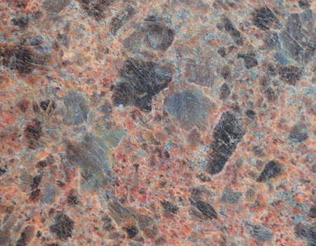 Natural brown granite with black splashes, closeup texture of dark stone. Background.