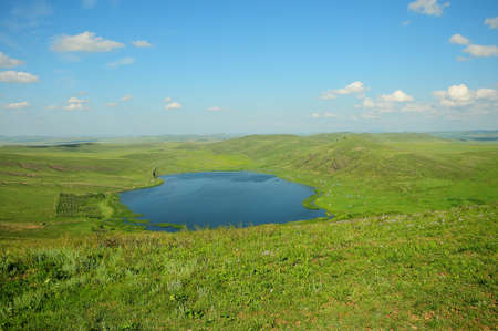 An endless picturesque valley with a beautiful lake surrounded by green hills. Shunet, Khakassia,...