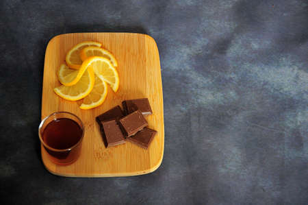 Wooden board with lemon, chocolate and a glass of cognac on a gray background. Close-up.の写真素材