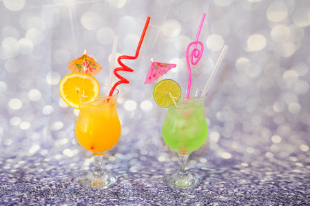 Two glasses of citrus juices with lime and orange slices on a gray shiny background. Close-up.の写真素材