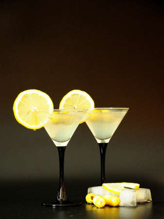 Two glasses of white vermouth with lemon slices and olives standing on a black background next to ice cubes. Close-up.の写真素材