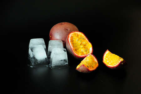 Passion fruit, ripe exotic fruit with ice cubes on a black background. Close-up.の写真素材