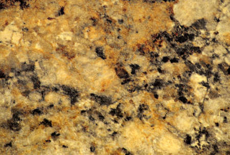 Golden marble with small black blotches, close-up of a flat polished natural stone surface....