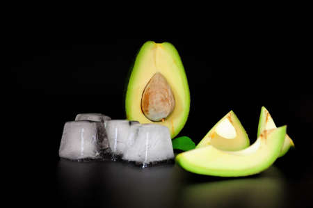 Ripe sliced avocado and melted ice cubes on a black background. Close-up.