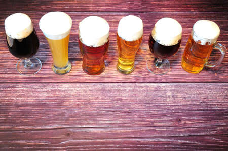 Six glasses of different types of beer are in a row on a wooden table. View from above.の写真素材