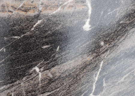 Black marble, polished shiny surface of natural stone with large brown veins. Background, pattern,...