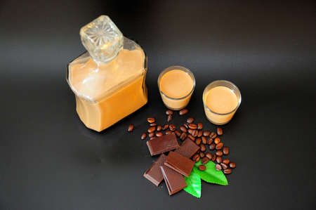 Homemade chocolate-coffee liqueur on a black background, roasted coffee beans and chocolate slices nearby. Close-up.の写真素材