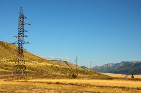 Tall metal poles of power lines run through the hills and steppe in early fall. Kuraiskaya steppe, Altai, Siberia, Russia.の写真素材