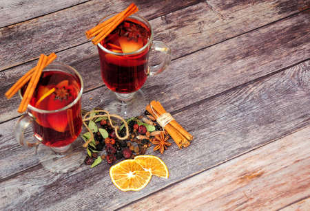 Two glasses of hot red wine with spices, orange slices and cinnamon sticks on a wooden table. Flat lay.の写真素材