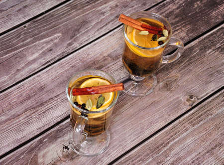 Two glasses of herbal tea with a slice of lemon, cinnamon and spices are on a wooden table. Top view, flat lay.の写真素材