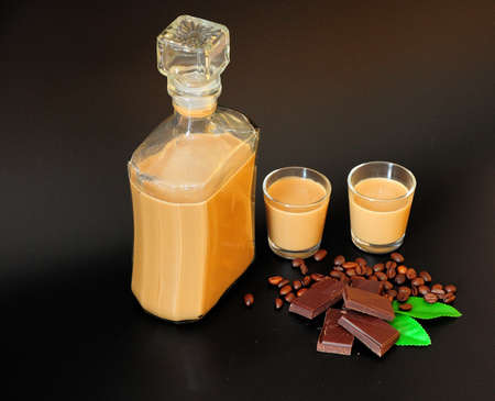 Chocolate coffee cream liqueur, homemade alcohol in a bottle and two glasses on a black background. close-up.の写真素材
