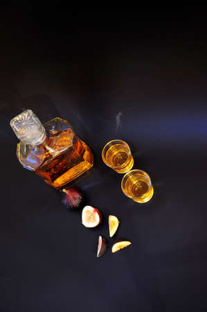 Fig liqueur, strong alcohol and pieces of ripe fruit on a black background. close-up.の写真素材