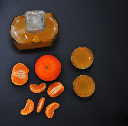 Mandarin liqueur, strong alcohol on a black background, next to pieces of ripe citrus. close-up.の写真素材