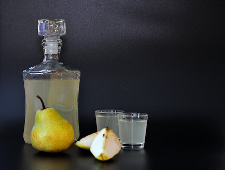 Pear Calvados, strong alcohol in a bottle and two glasses on a black background, next to ripe fruits. close-up.の写真素材