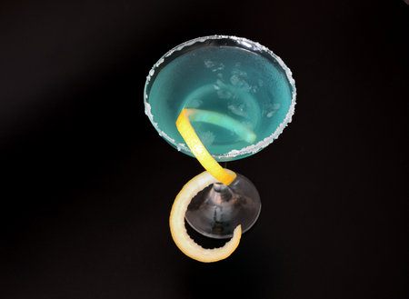 Blue Curacao, tall glass with alcohol, sugar around the rim and lemon zest on a black background. close-up.の写真素材