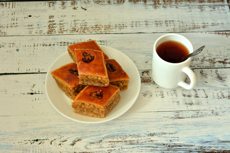 Delicious fresh baklava, a plate with oriental sweets and a cup of hot tea on a light wooden table. close-up.の写真素材