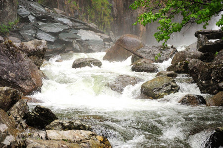 Huge stones in the bed of a stormy river flowing in a swift stream from the mountains. Korbu waterfall, Altai, Siberia, Russia.の写真素材