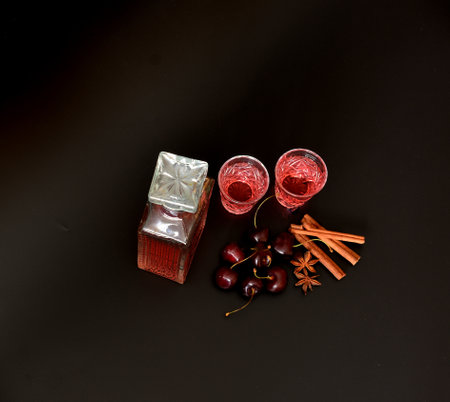 Cherry liqueur with spices, homemade alcohol in a crystal decanter and two glasses with cinnamon and...
