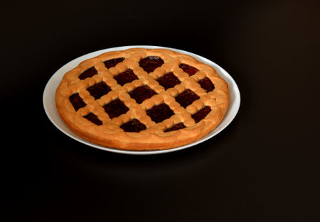 Italian cherry pie on a black background, a delicious dessert on a large white ceramic plate. Close-up.の写真素材