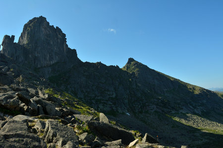 A ridge of high cliffs casts a shadow from the rising sun over a picturesque valley on a sunny...