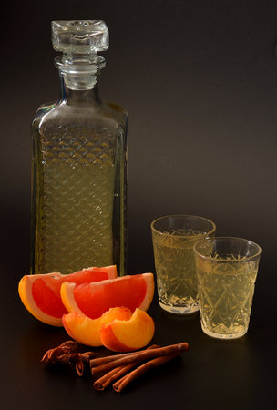 Juice from ripe fruits with ice in a tall glass on a black background, next to pieces of peach and grapefruit. Close-up.の写真素材