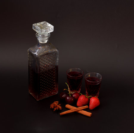 Berry liqueur made from strawberries and cherries with cinnamon and anise in crystal glass on black background. Close-up.の写真素材