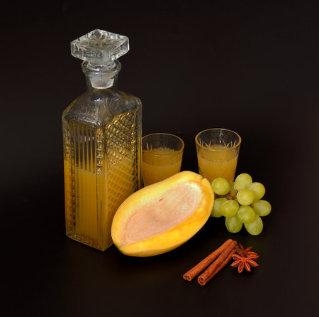 Fruit liqueur made from mango and green grapes with cinnamon and anise in crystal glass on black background. Close-up.の写真素材