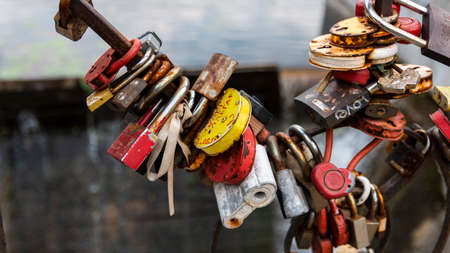 Multicolored padlocks hanging on a bridge on a lake backgroundのeditorial素材