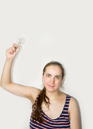 Casual woman holding a  lightbulb isolated on grey backgroundの写真素材
