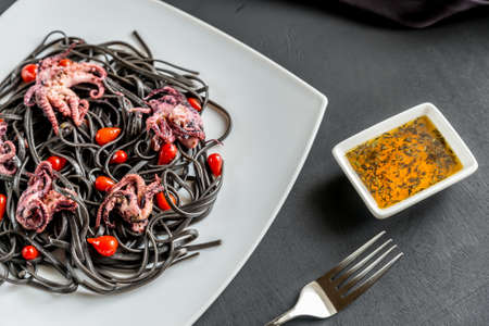 Black pasta with octopus and peppersの写真素材
