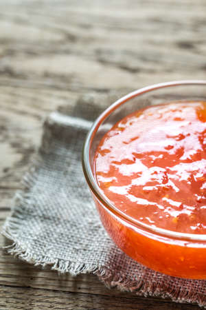 Glass bowl of thai sweet chili sauce on the wooden backgroundの写真素材