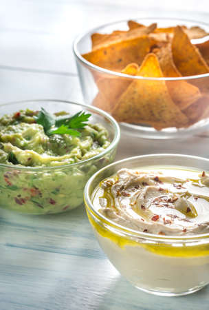 Bowls of hummus and guacamole with tortilla chipsの写真素材