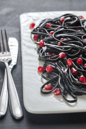 Black pasta with pomegranate seedsの写真素材