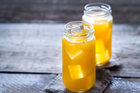 Glass jars of mango juice with ice
