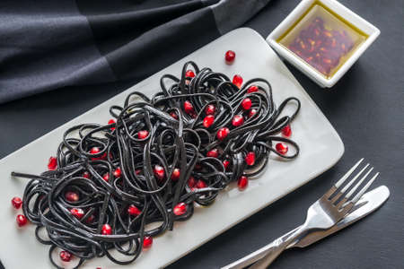 Black pasta with pomegranate seeds