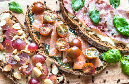 Bruschetta with different toppings on the wooden boardの写真素材