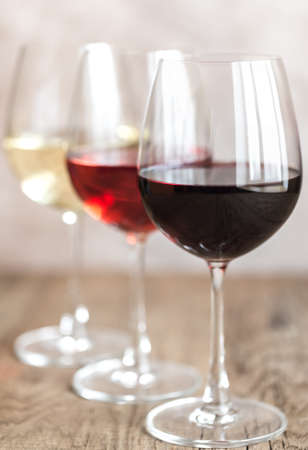 Glasses of red, rose and white wine on the wooden backgroundの写真素材