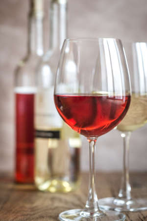 Glasses of rose and white wine on the wooden backgroundの写真素材