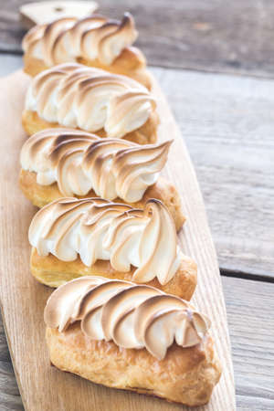 Eclairs with lemon curd and meringue on the wooden board