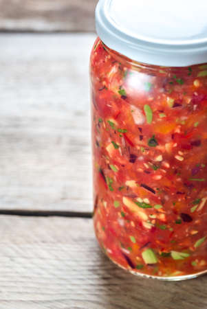 Jar of salsa on the wooden background