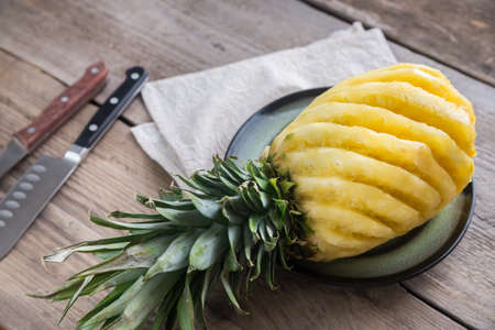 Pineapple on the plate on the wooden backgroundの写真素材